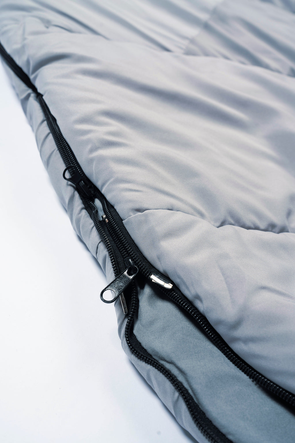 Close-up of a light grey 'SnoozePod' – a wearable sleeping bag with a double zipper for side and base openings