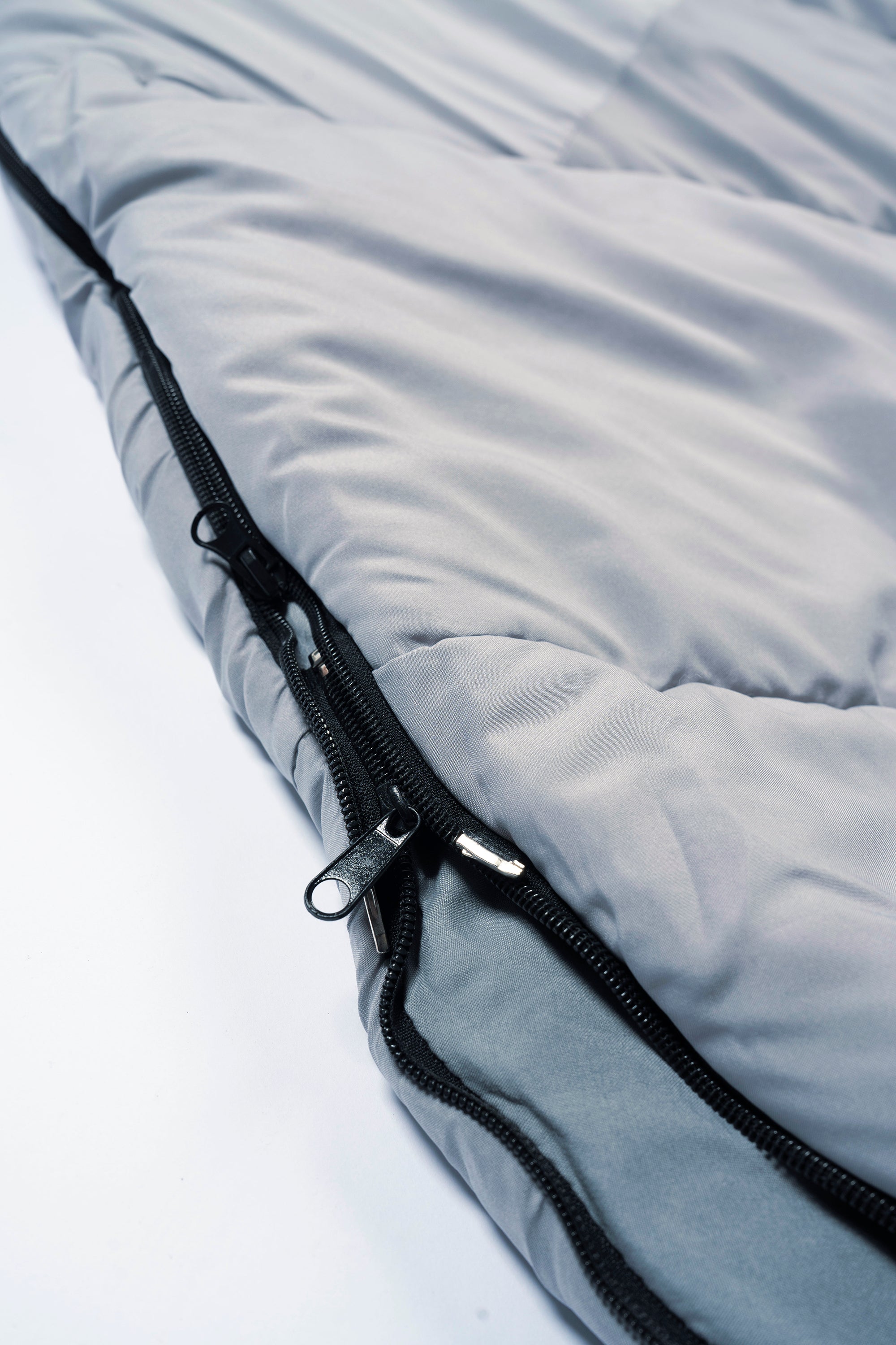 Close-up of a light grey 'SnoozePod' – a wearable sleeping bag with a double zipper for side and base openings
