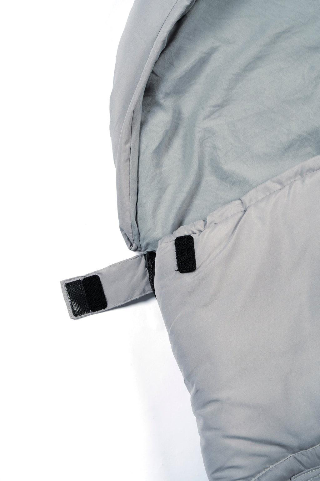 Close-up of a light grey wearable sleeping bag's side zipper and fastener